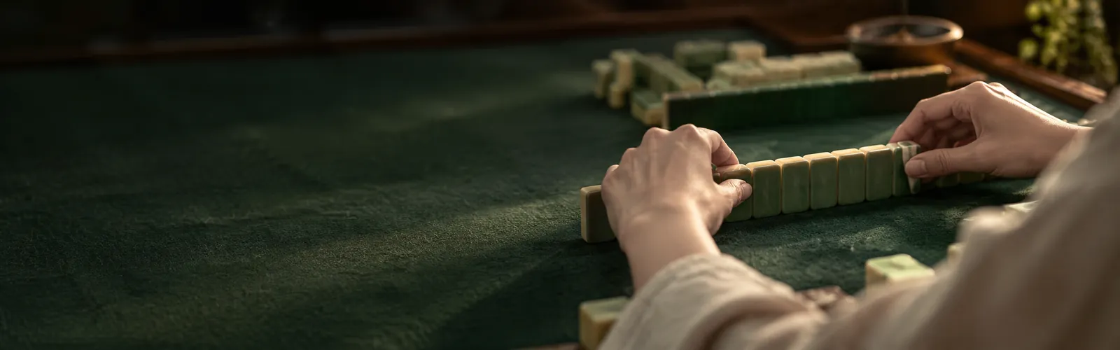 Manos de un jugador ordenando sus fichas de mahjong